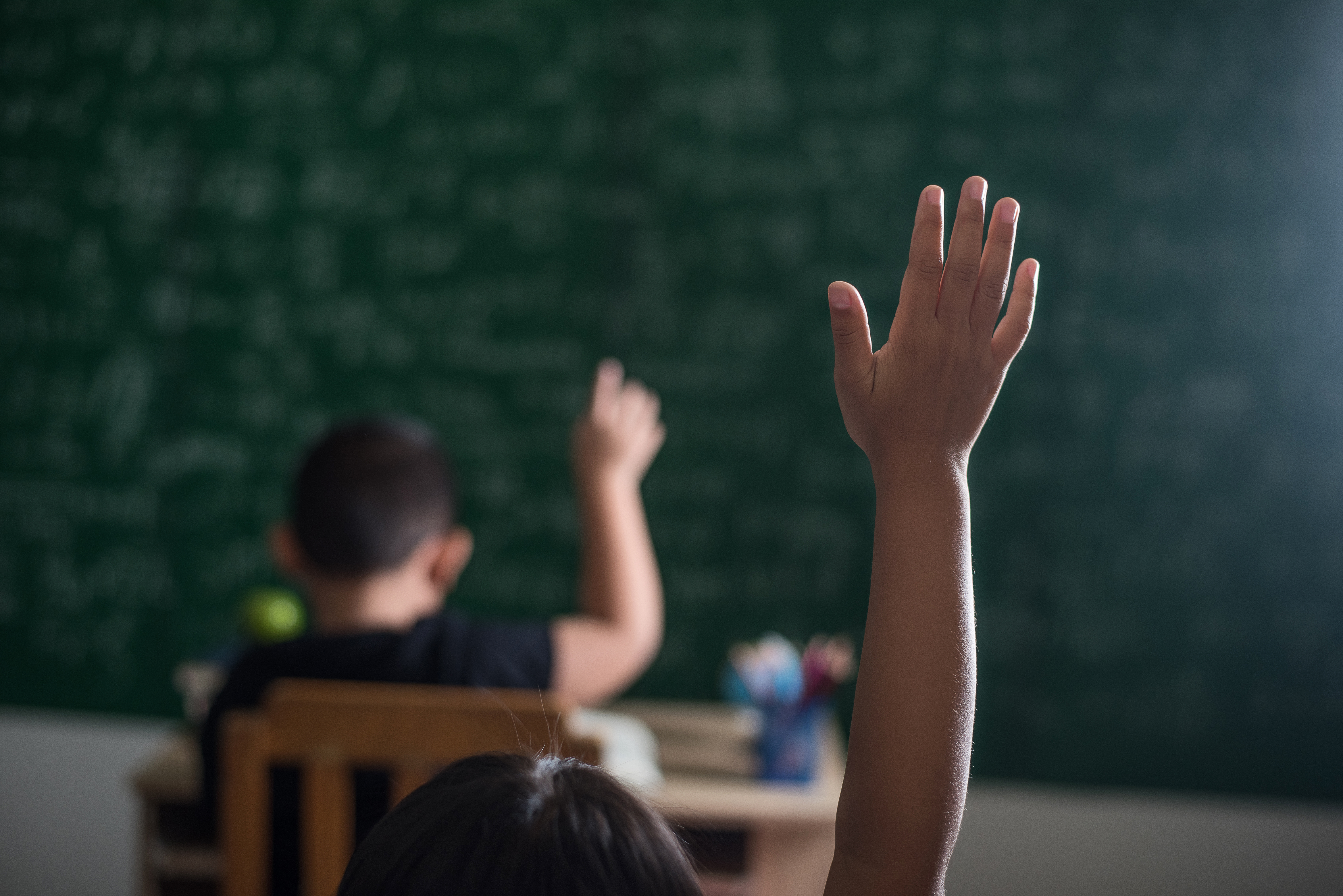 Children With Raised Hands In Classroom